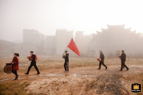 A traditional wedding band walks through rural Jishui County, Jiangxi Province, China, accompanying the wedding procession with instruments and a red flag